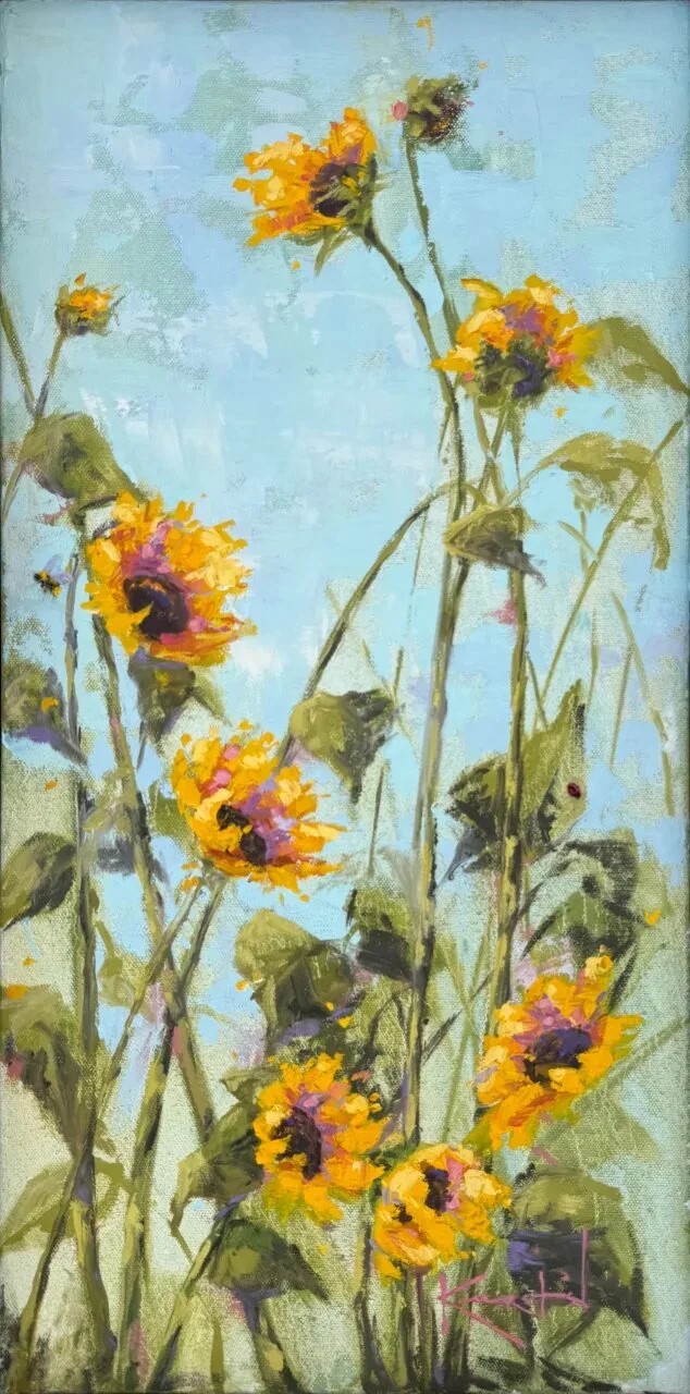 Yellow sunflowers on tall green stalks reaching upward against pale blue sky