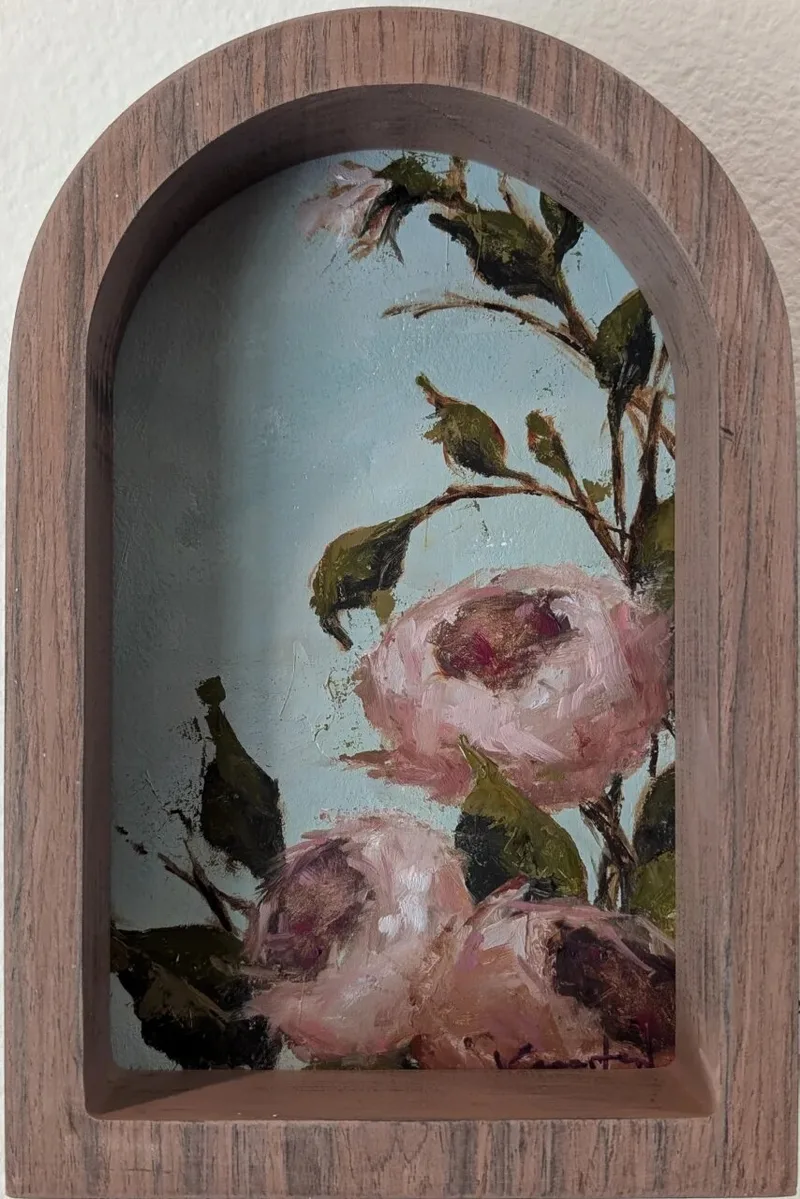 Pink roses with green leaves painted inside an arched wooden frame niche