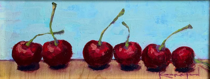 A row of red cherries with stems lined up on a pale blue background, wide panoramic format.