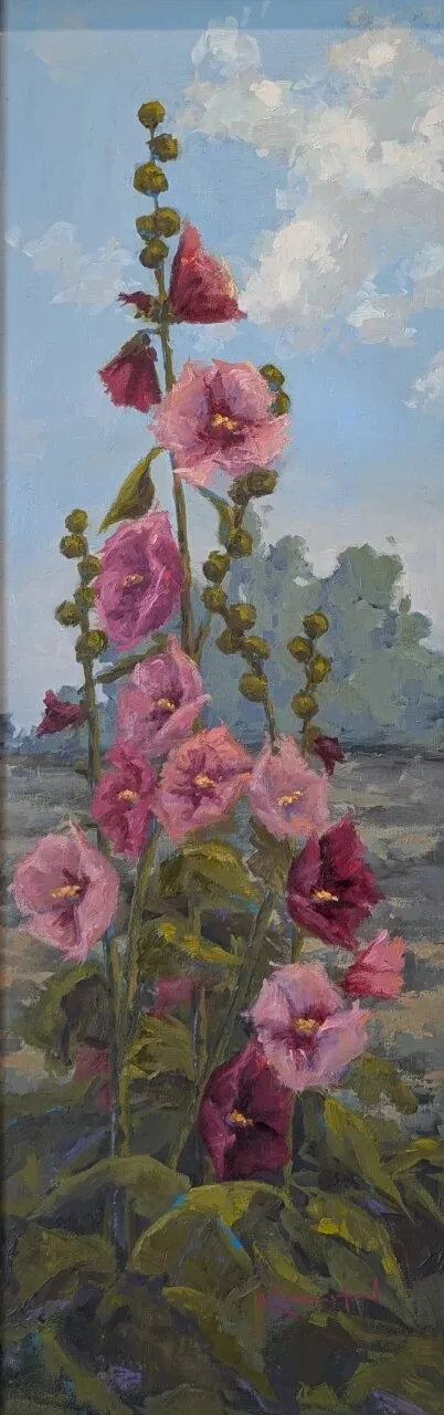 Tall pink and magenta hollyhocks against a cloudy summer sky with distant trees.