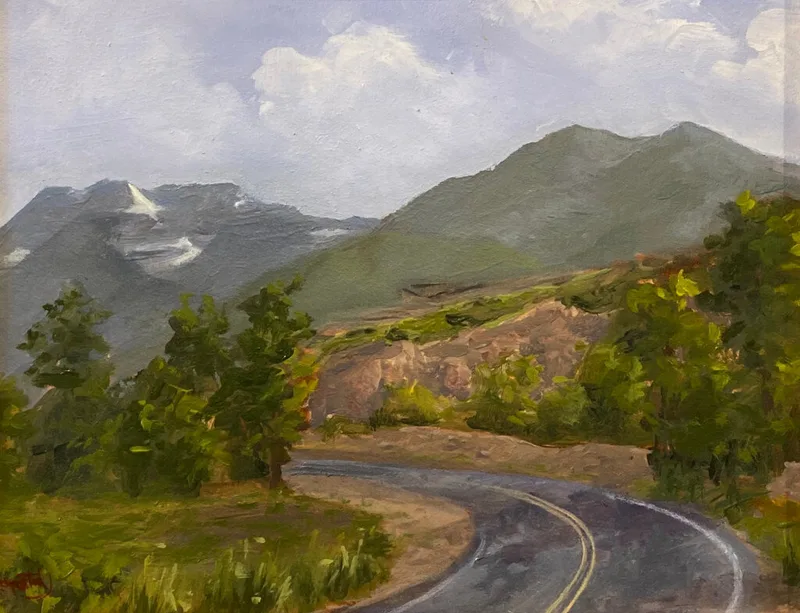 Curving paved road winding through green hillsides toward distant snow-capped mountains