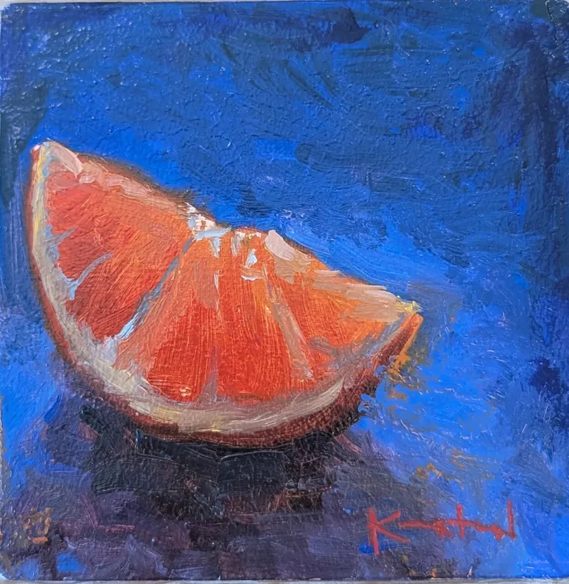Bright orange citrus slice on deep blue surface with luminous translucent flesh