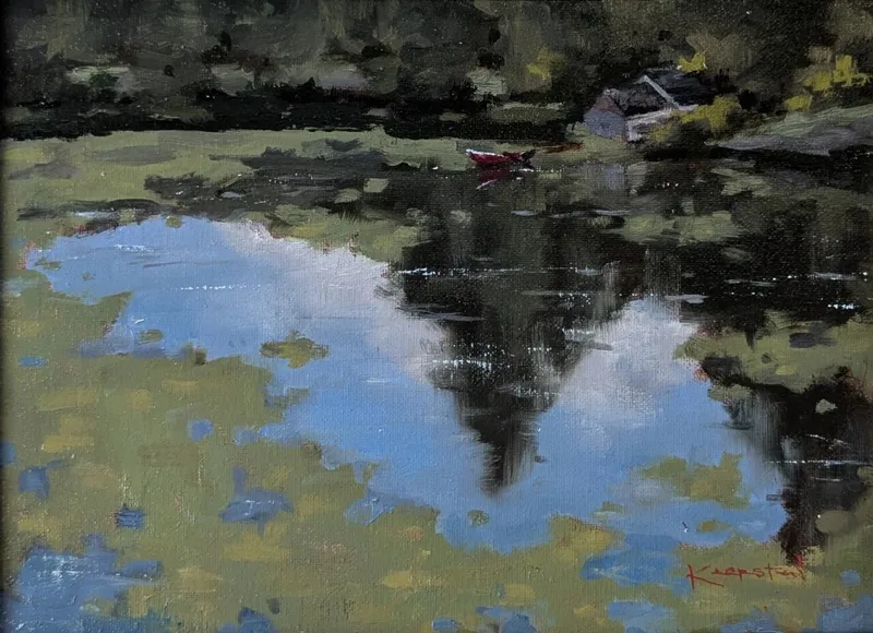 Still pond reflecting trees and sky with small red boat near shore