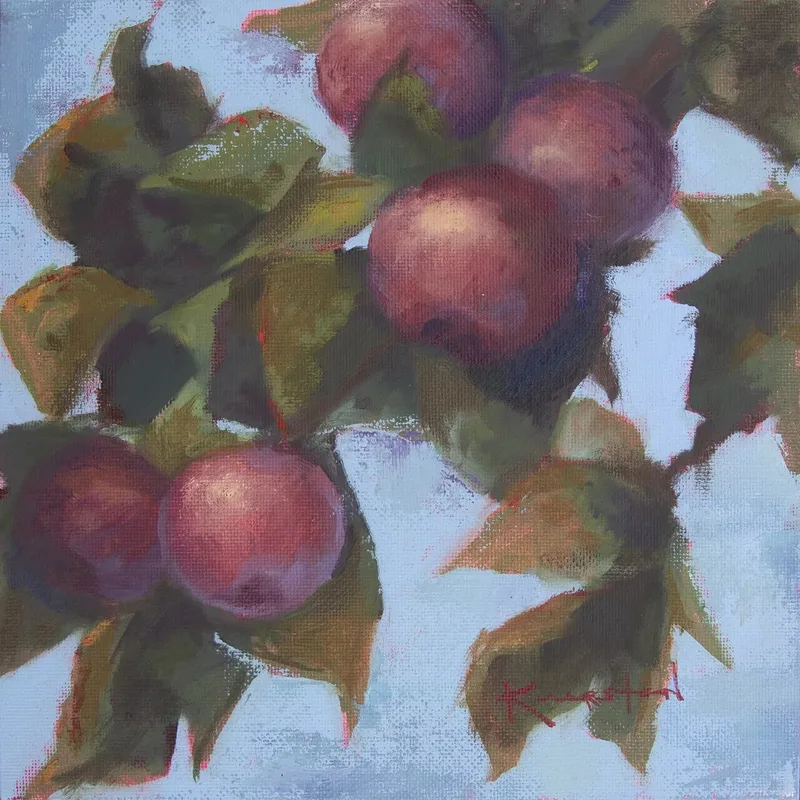 Cluster of dusky purple plums hanging among green leaves against soft pale background