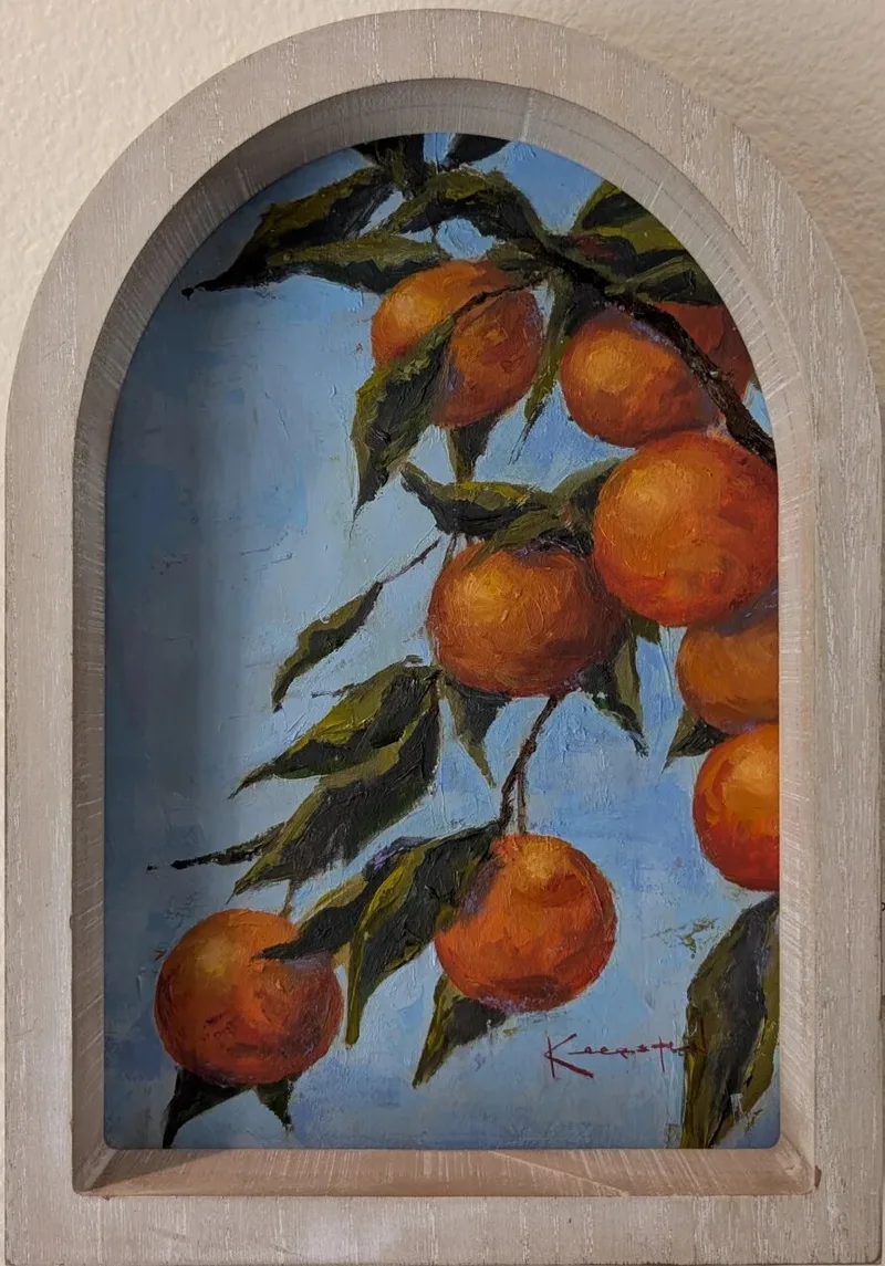 Orange fruit clusters hanging from leafy branches against blue sky in arched frame