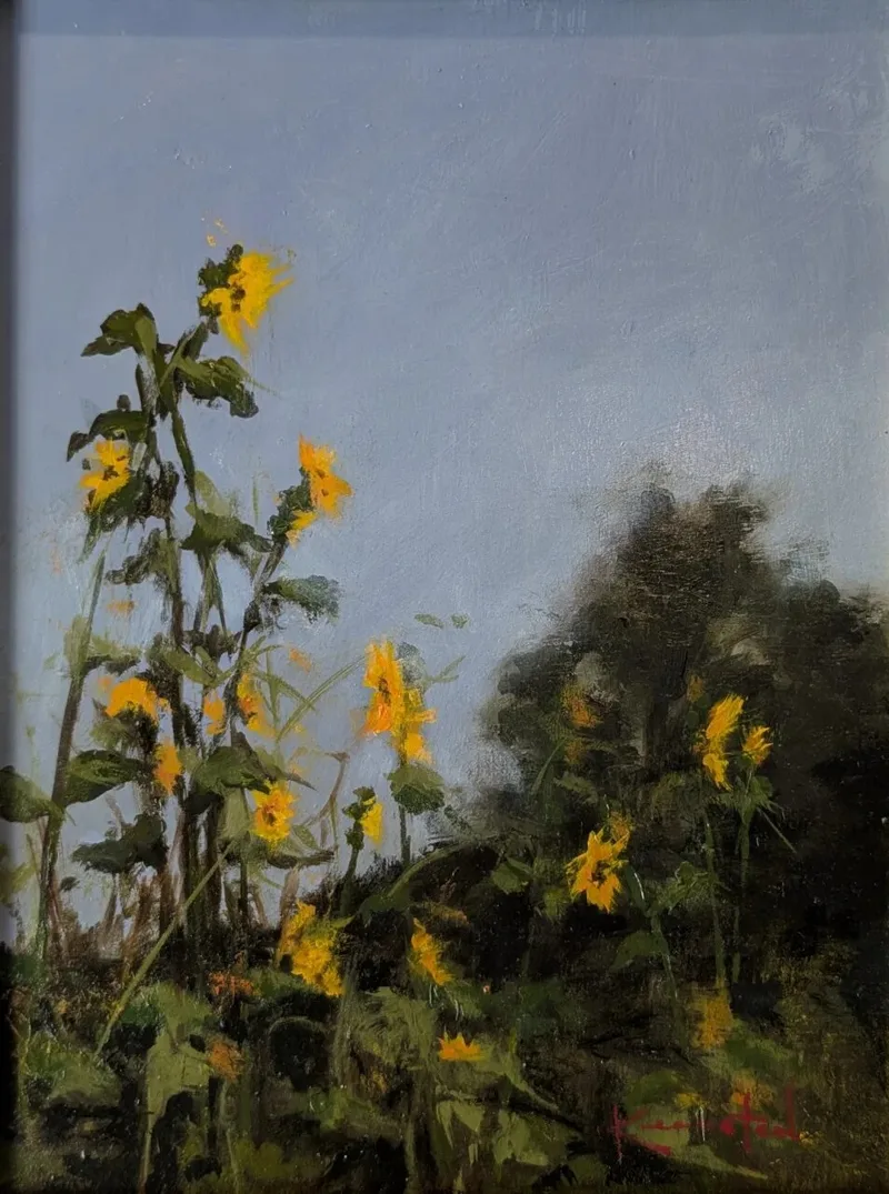 Yellow sunflowers growing on a hillside against soft gray blue sky